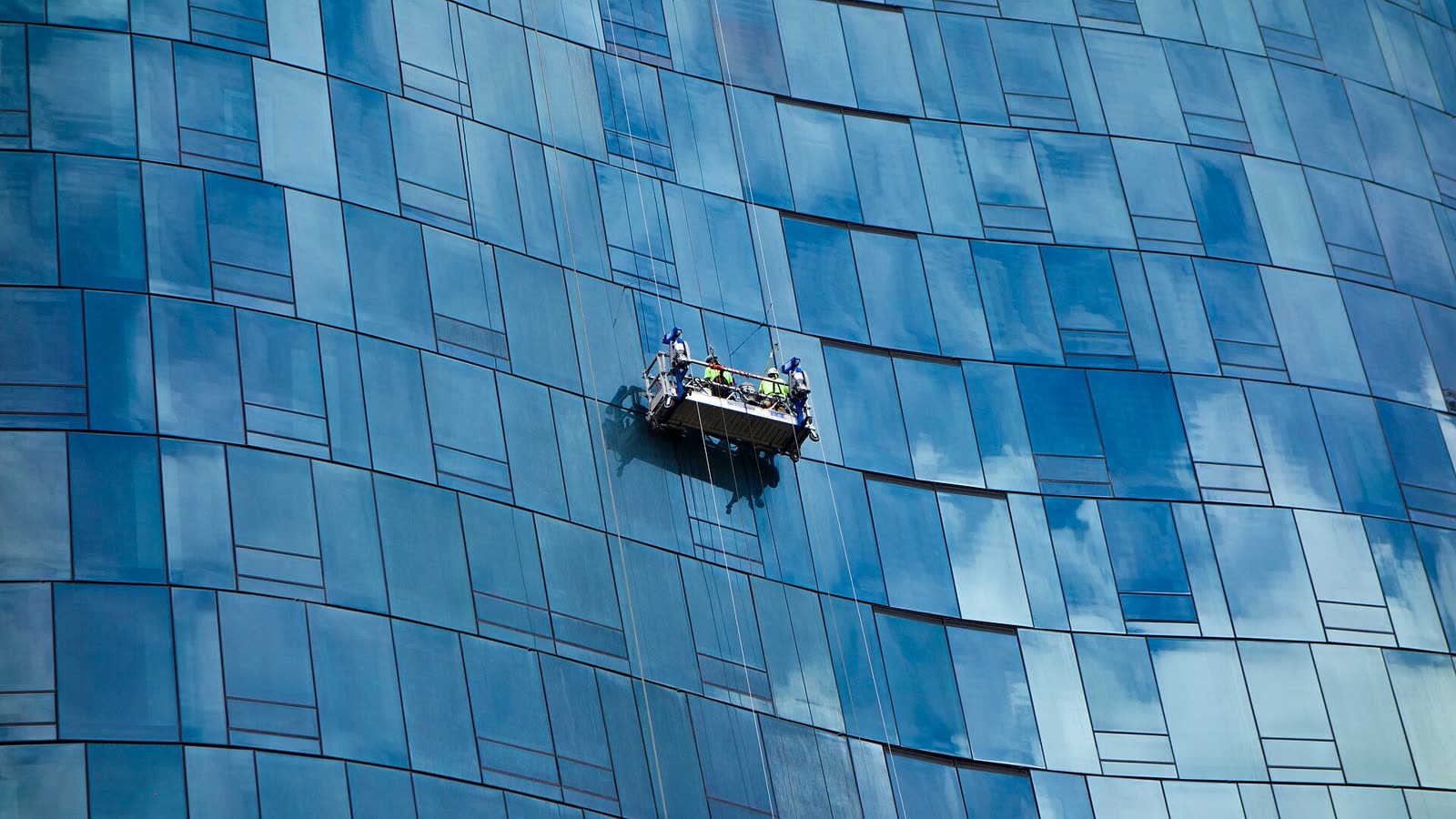 Blaue Glasfassade mit Arbeitskorb vor den Fensterbändern
